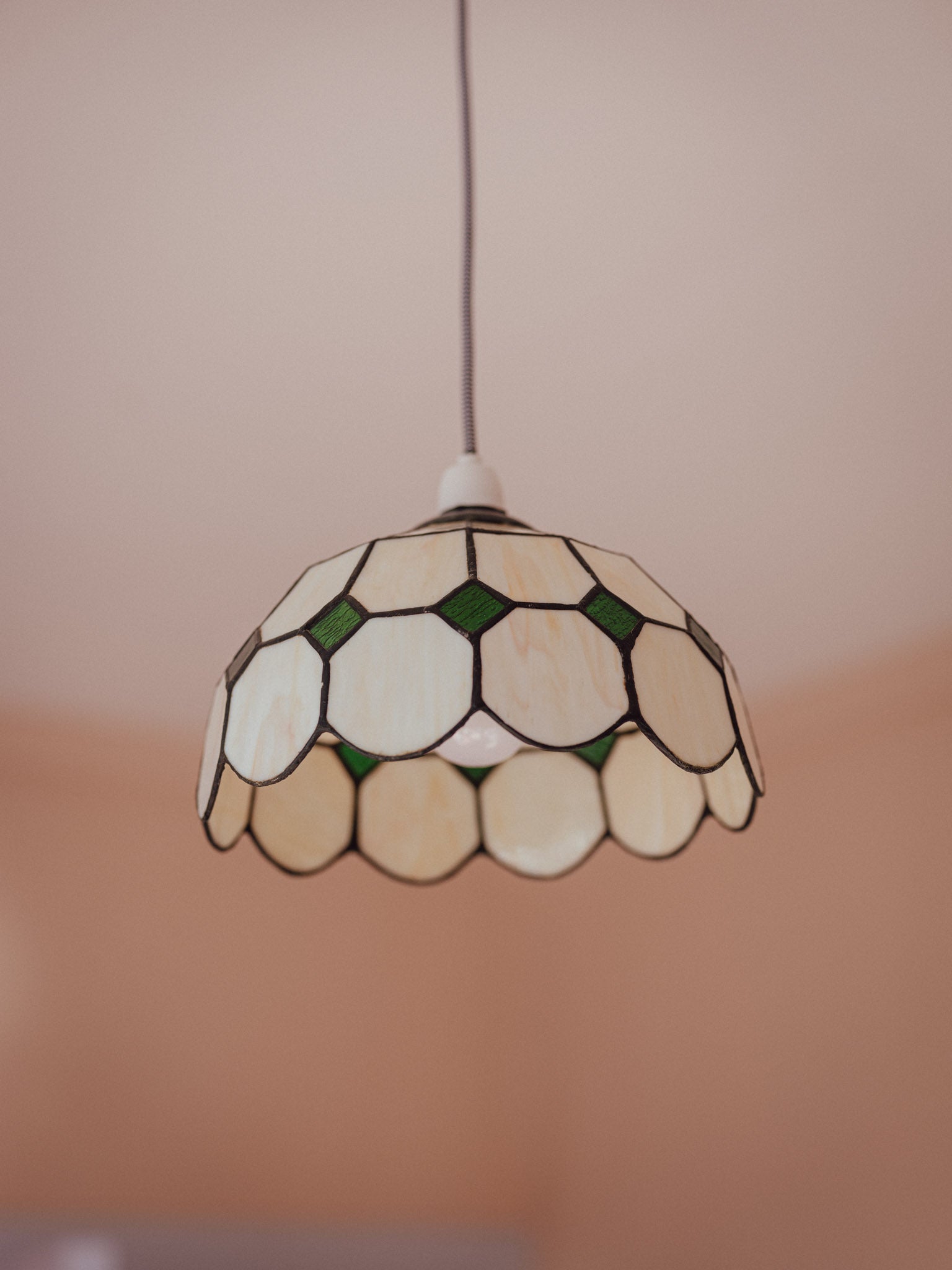 Stained glass pendant light with a geometric pattern on a neutral background