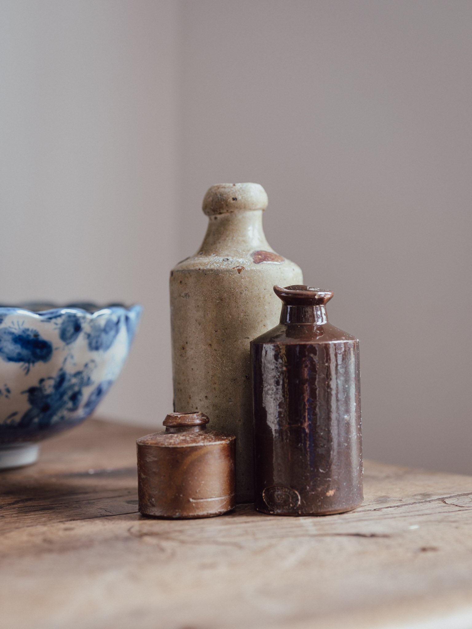 Three ceramic bottles on a wooden surface with a plain background