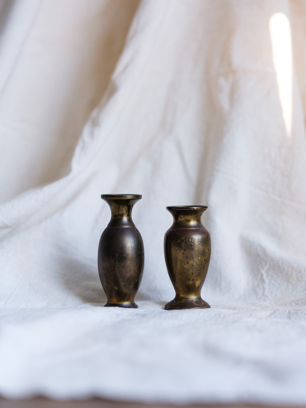 Two bronze vases on a white fabric background