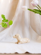 Dog figurine on a white surface with tulips and green leaves in the background