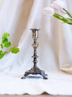 Decorative candlestick on a white fabric background with flowers and leaves.