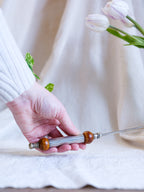 Hand holding a wooden-handled tool with a blurred white background