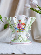 Decorative ceramic vase with floral design on a white fabric background