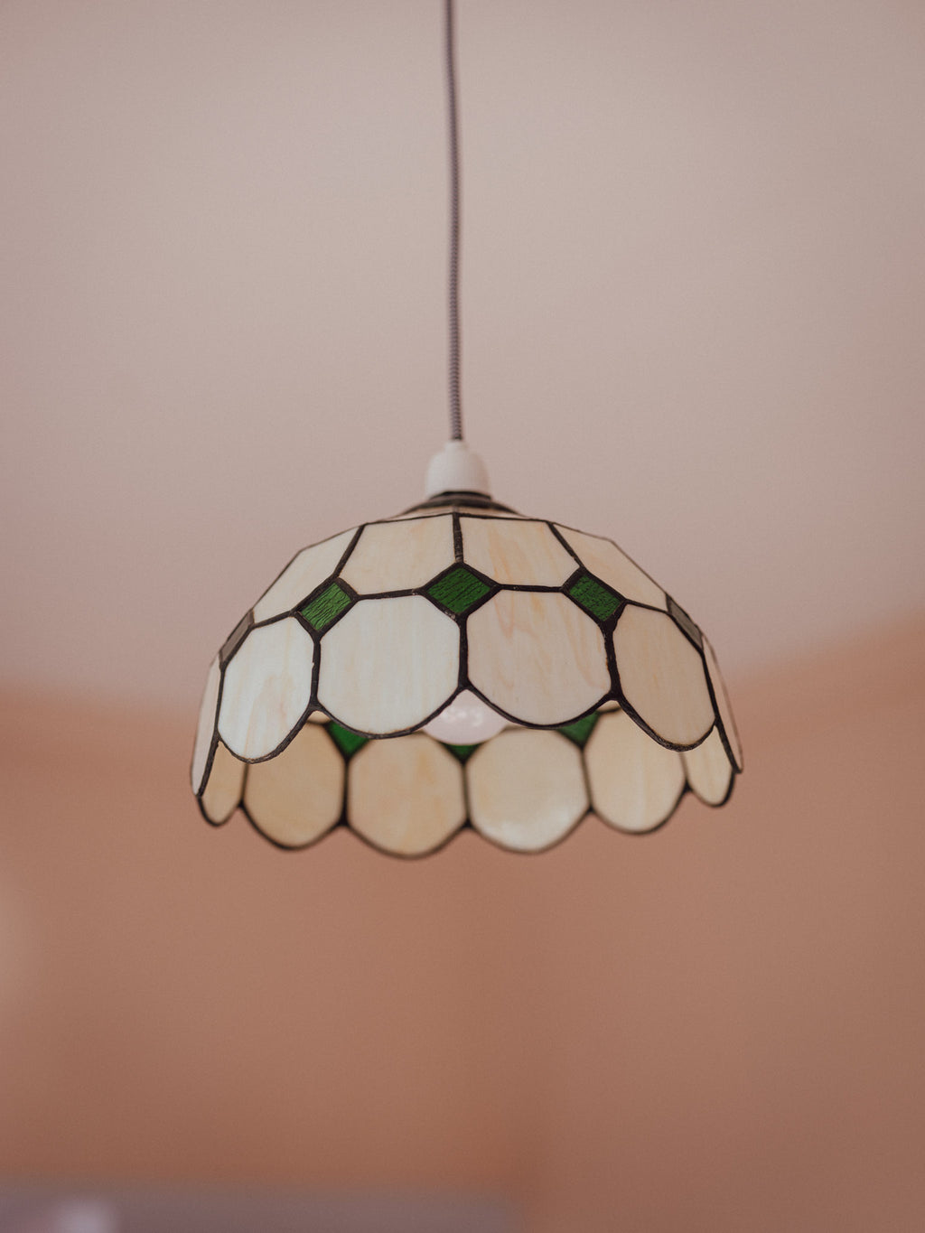 Stained glass pendant light with a geometric pattern on a neutral background