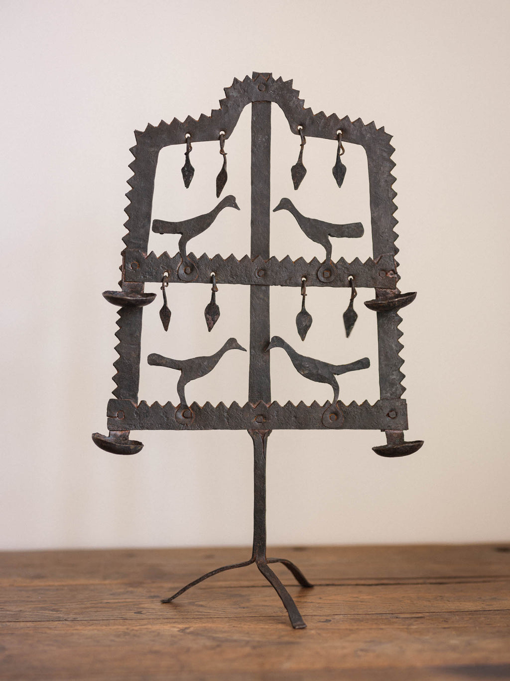 Decorative metal stand with bird silhouettes on a wooden surface