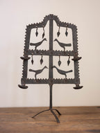 Decorative metal stand with bird silhouettes on a wooden surface
