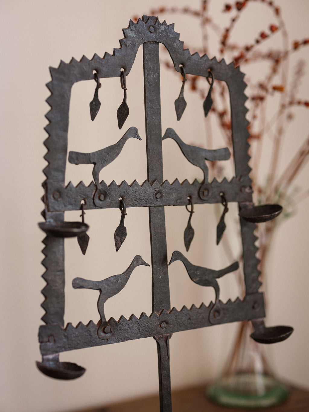 Decorative metal stand with cut-out bird designs against a neutral background