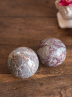 Two marbled stones on a wooden surface with a blurred plant in the background