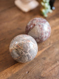 Two marbled stone spheres on a wooden surface