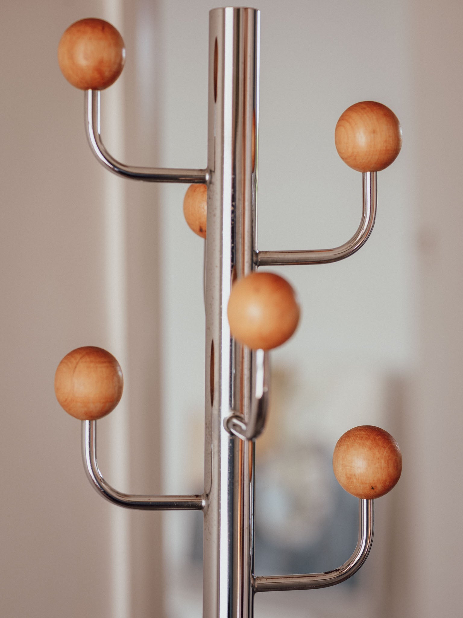 Metal coat rack with wooden hooks on a neutral background