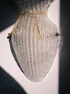 Vintage Murano glass wall sconce with ribbed clear glass and gold ribbon detailing. Italian mid-century wall light, hand-blown using the Graniglia technique. Mounted on a light grey backplate with brass fittings, perfect for hallways, bedrooms, or statement lighting.
